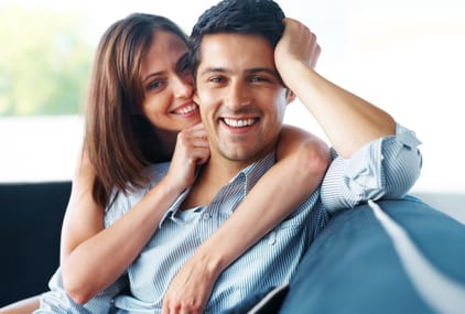 Portrait of a beautiful young couple sitting together on couch at home - Indoor